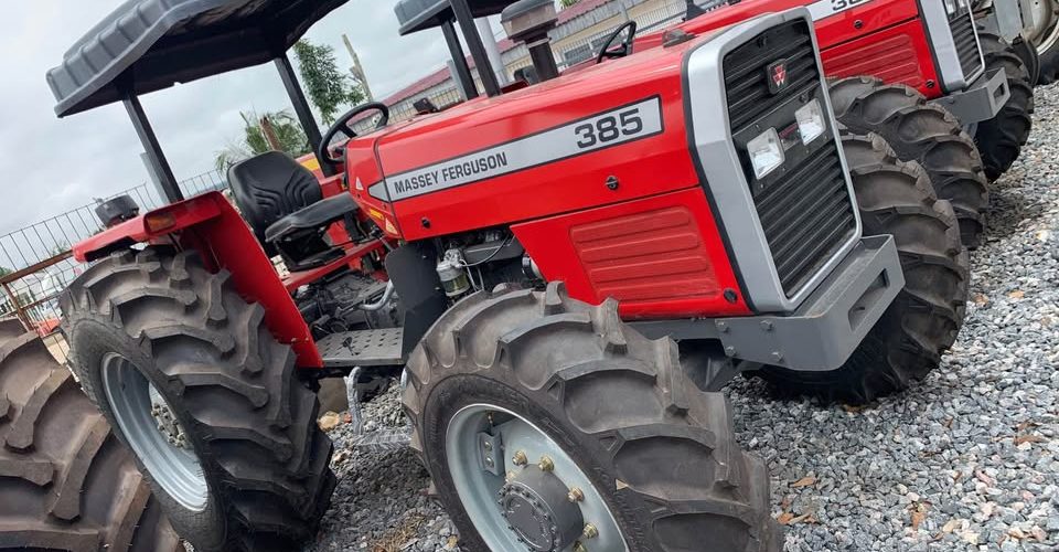 farm-tractor-nigeria-960x500- - Tractors for Sale in Nigeria Red Massey Ferguson 385 tractor with large rear tires parked on a gravel lot, lined up with other tractors in the background.